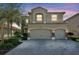 Two-story home featuring a three car garage, a brick paver driveway, and manicured landscaping at 2495 Oakwood Preserve Dr, Wesley Chapel, FL 33543
