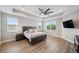 Spacious main bedroom featuring a tray ceiling, ceiling fan, wood floors, and plenty of natural light from multiple windows at 2495 Oakwood Preserve Dr, Wesley Chapel, FL 33543