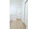 Bright hallway featuring light wood floors and white walls, leading to a white door with black hardware at 4332 Har Paul Cir, Tampa, FL 33614