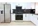 Modern kitchen featuring stainless steel fridge and range, complemented by stylish white cabinets and sleek black countertops at 4332 Har Paul Cir, Tampa, FL 33614
