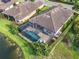 Aerial view of a private screened in pool surrounded by lush landscaping and adjacent to a serene lake at 4506 Stickley Ct, Palmetto, FL 34221