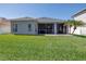 Well-maintained backyard with lush green grass, screened-in patio, and tropical landscaping at 511 York Dale Dr, Ruskin, FL 33570