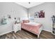 Cozy bedroom showcasing a bed with pink blanket, white nightstand, and wood-look flooring at 511 York Dale Dr, Ruskin, FL 33570