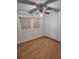 Cozy bedroom features wood-look floors, ceiling fan, neutral walls and a bright window at 6012 Frond Way, Apollo Beach, FL 33572