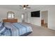 Primary bedroom featuring a ceiling fan, TV, ensuite bath, and comfortable carpet at 662 Petal Mist Ln, Brooksville, FL 34604
