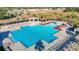 A beautiful community pool with palm trees and ample seating and a covered lounging area on a sunny day at 662 Petal Mist Ln, Brooksville, FL 34604