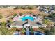 Aerial view of a community clubhouse and large cross-shaped pool with lounge chairs and palm trees at 662 Petal Mist Ln, Brooksville, FL 34604