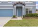 Charming blue home with a manicured lawn, featuring a well-kept front yard, garage, and welcoming entrance at 662 Petal Mist Ln, Brooksville, FL 34604