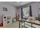 Cozy bedroom with toy kitchen, lavender walls, ceiling fan, window with backyard view, and ample toys at 7511 Turtle View Dr, Ruskin, FL 33573