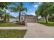 Beautiful home with a lush green lawn, mature palm trees, and a spacious two-car garage at 7511 Turtle View Dr, Ruskin, FL 33573