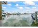 A waterfront view featuring a boat docked alongside waterfront homes under a sunny, partly cloudy sky at 7889 3Rd S Ave, St Petersburg, FL 33707