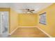 Bedroom with yellow walls, a ceiling fan, wood-look floors, and a bright window, adjacent to a bathroom space at 226 75Th N St, St Petersburg, FL 33710