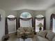 Bright living room with large windows, comfortable seating, and soft natural light at 11185 Heathrow Ave, Spring Hill, FL 34609