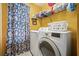 Bright laundry room with yellow walls, washer, dryer, and open shelving for storage at 11519 Cypress Reserve Dr, Tampa, FL 33626
