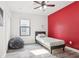 Cozy bedroom with wood-look floors, a ceiling fan, and a bright red accent wall at 14227 Alistar Manor Dr, Wimauma, FL 33598