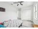 This bedroom boasts a ceiling fan, light plank flooring, closet, and a sunlit window at 14227 Alistar Manor Dr, Wimauma, FL 33598