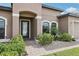 Home's welcoming entryway with arched doorway, manicured bushes, and a brick path at 14227 Alistar Manor Dr, Wimauma, FL 33598