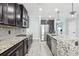 Spacious kitchen featuring dark cabinets, stainless steel appliances, granite countertops, and light wood floors at 14227 Alistar Manor Dr, Wimauma, FL 33598