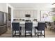 A bright kitchen features white cabinets, a quartz countertop island with chairs, and stainless steel appliances at 14423 Meadow Bird Ave, Riverview, FL 33579
