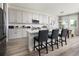 A bright kitchen features white cabinets, a quartz countertop island with chairs, and stainless steel appliances at 14423 Meadow Bird Ave, Riverview, FL 33579