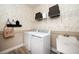 Functional laundry room with modern washer and dryer, storage shelves, sink, and patterned wallpaper at 14423 Meadow Bird Ave, Riverview, FL 33579