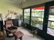 Inviting sunroom features a comfortable chair, decor, and views of the outdoors through expansive windows at 2513 Oakleaf Ln # 26C, Clearwater, FL 33763