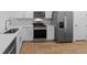 Bright kitchen featuring stainless steel appliances, white cabinets, and wood floors at 27153 Capri Shores Cir, Englewood, FL 34223
