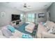 Cozy living room featuring a sofa, ottoman, rug, TV, and sliding glass doors to the balcony at 3 7Th Ave # 3, Indian Rocks Beach, FL 33785