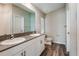 Bathroom featuring a double vanity, stone countertops, wood-look flooring, and a large mirror at 37171 Sagemoor Dr, Zephyrhills, FL 33541