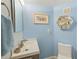 Charming powder room with blue walls, white fixtures, and decorative shelving for added storage at 4212 Mill Valley Ct, Tampa, FL 33618