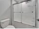 Bathroom showcasing a white toilet and bathtub with a sliding glass door and neutral tile at 4513 Eternal Prince Dr, Sun City Center, FL 33573