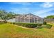 Backyard featuring a screened porch with a well-maintained lawn and lush landscaping at 5212 Twin Creeks Dr, Valrico, FL 33596