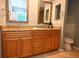 Bathroom featuring double sinks with granite countertops, wooden cabinets, and a commode at 5348 Saddlebrook Way # 2, Wesley Chapel, FL 33543