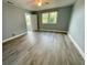 Well-lit bedroom with gray walls, ceiling fan, and vinyl floors; a doorway provides a view into another room at 55 Harbor View Ln # 108, Belleair Bluffs, FL 33770