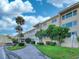 Well-maintained building featuring lush landscaping, mature trees, and ample parking at 55 Harbor View Ln # 108, Belleair Bluffs, FL 33770