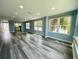 Bright living room with modern gray wood flooring and lots of natural light from large windows at 55 Harbor View Ln # 108, Belleair Bluffs, FL 33770