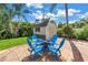 Backyard with shed features a stone paver patio and blue Adirondack chairs surrounding a fire pit at 6630 Gulfport S Blvd, South Pasadena, FL 33707
