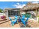 Paver patio in backyard features Adirondack chairs, tiki bar, and covered porch at 6630 Gulfport S Blvd, South Pasadena, FL 33707