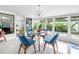 Cozy dining area with a glass-top table, blue upholstered chairs, and large windows overlooking lush greenery at 6630 Gulfport S Blvd, South Pasadena, FL 33707