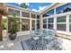 Backyard outdoor living space with a dining table, tiki hut, and attached sunroom with many windows at 6630 Gulfport S Blvd, South Pasadena, FL 33707