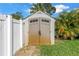 Close-up of the outdoor storage shed with a double door, next to a white fence at 6630 Gulfport S Blvd, South Pasadena, FL 33707