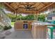 Thatched-roof tiki bar with ceiling fan, bamboo accents, and stone countertop is a perfect outdoor entertaining spot at 6630 Gulfport S Blvd, South Pasadena, FL 33707