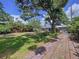 Expansive backyard featuring lush green grass, mature trees, a brick walkway, and a glimpse of the home's exterior at 6920 Bougainvilla S Ave, St Petersburg, FL 33707