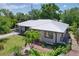 Charming home featuring a modern metal roof, landscaped yard with mature palms, and a brick walkway at 6920 Bougainvilla S Ave, St Petersburg, FL 33707