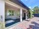 Cozy covered patio featuring brick flooring, providing a serene outdoor relaxation space with a chair and lush greenery backdrop at 6920 Bougainvilla S Ave, St Petersburg, FL 33707