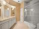 Well-lit bathroom with decorative wallpaper, granite counters, and a shower-tub combo with glass doors at 876 Ranch Rd, Tarpon Springs, FL 34688