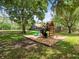 A wooden playground set with slide surrounded by mature trees at 876 Ranch Rd, Tarpon Springs, FL 34688