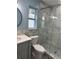 A modern bathroom featuring glass shower doors, a stone floor, a vanity and round mirror at 11096 117Th Way, Seminole, FL 33778