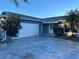 A single-story home with an attached garage, landscaping, and blue exterior paint at 11096 117Th Way, Seminole, FL 33778