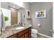 Bathroom with granite counters, wood cabinets, decorative mirror, and tiled shower at 11142 Spring Point Cir, Riverview, FL 33579
